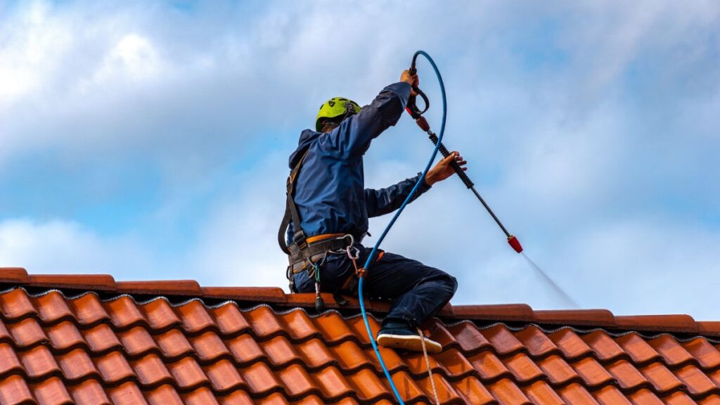 Specialist reinigt dak met hogedrukspuit 